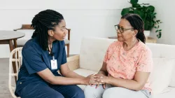Two Black women, one a nurse and one a patient, discuss treatment.