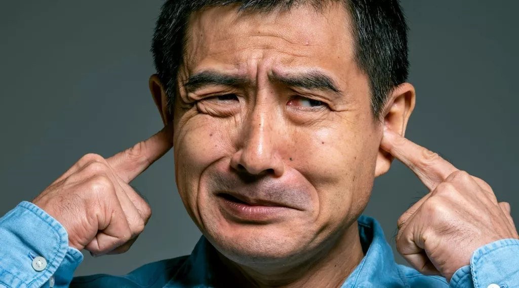 A man plugging his ears with his fingers. 