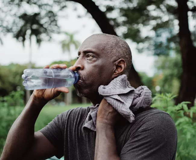 black man drinking water on hot day