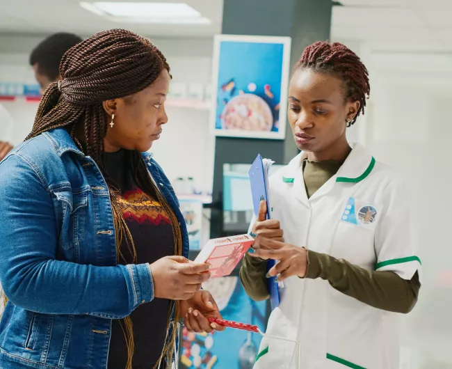black woman receiving medicine from black female pharmacist