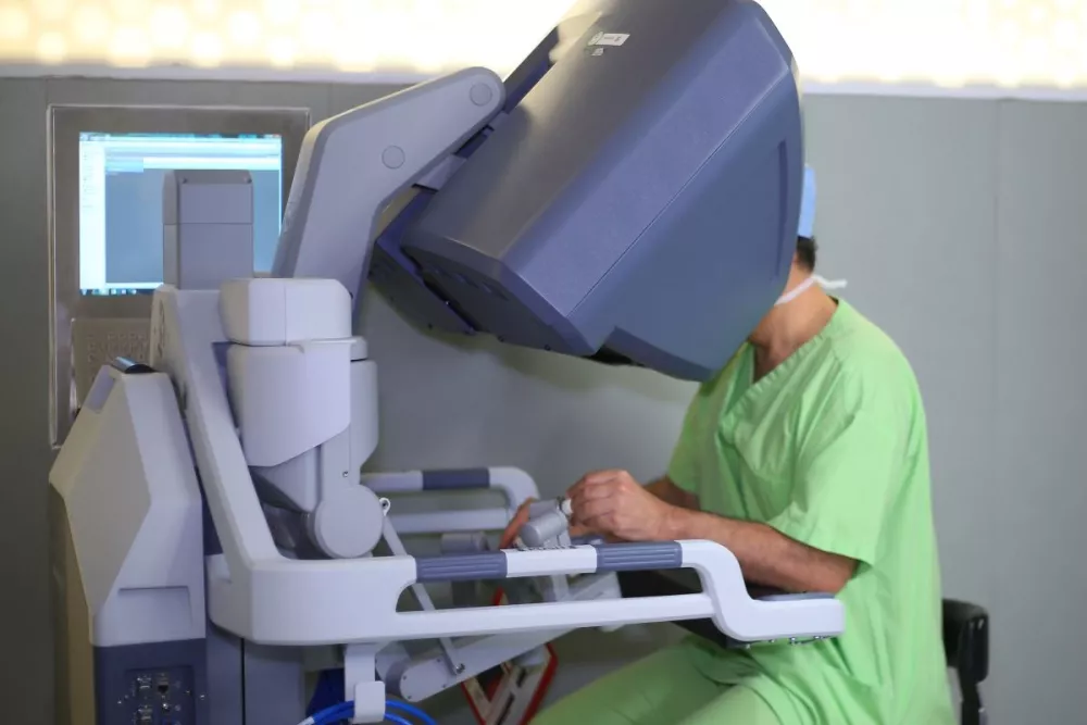 A surgeon uses a console to control a robotic surgery machine. 
